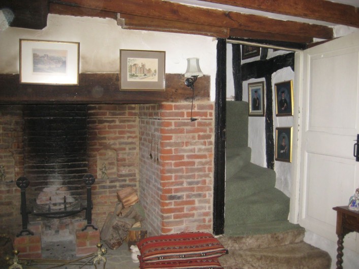 Inserted chimney with large open ground floor fireplace. The staircase to the side twists tightly around the flue providing access to the newly created room above this former open hall. The low height of the tie beam prevented access from this staircase initially to the first floor room beyond which would have always been accessible directly by an open ladder type stair. Later alterations after the new wing to the side was built, included cutting through the tie beam to allow access to both rooms from this staircase.