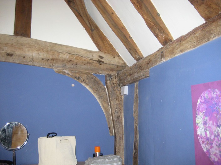 The cross wing central tie beam at first floor level showing the lack of studs and decorative curved braces indicating that this room was open as a single room with central exposed truss. The side wall contains the chimney breast which was inserted later.